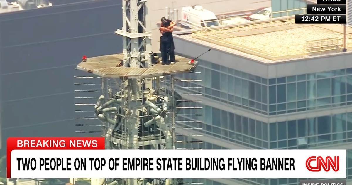 Two people climb to the top of NYC's Empire State Building. Then one got down on one knee