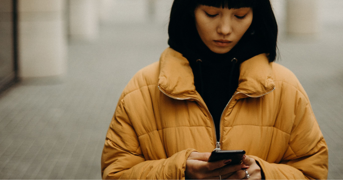 A young woman looking at her phone in disappointment.