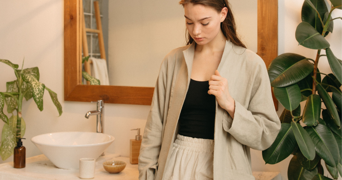 A woman standing with a cast-down expression waiting for someone inside a restroom.