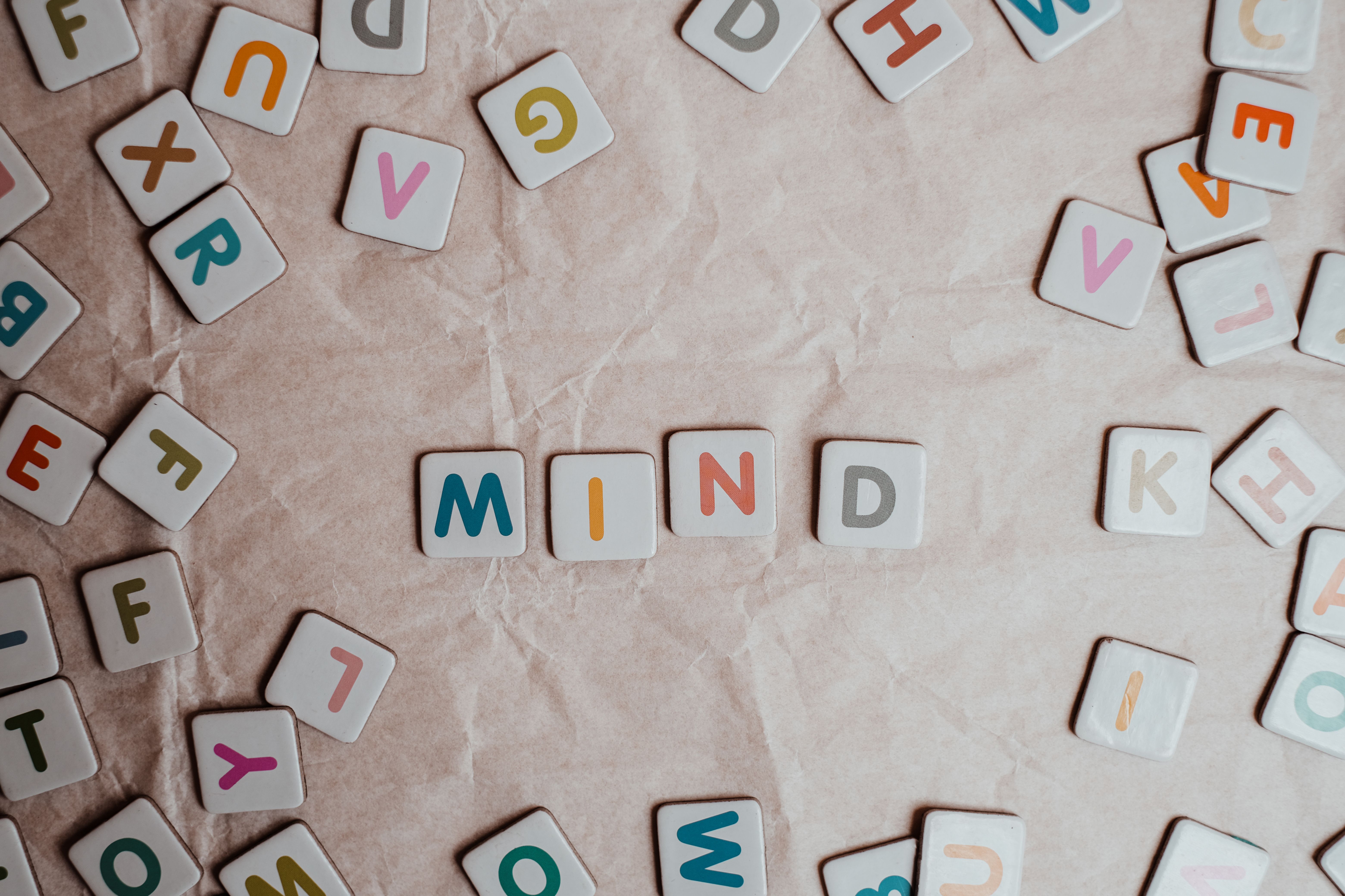 Close-up of scattered letter tiles spelling 'mind' on crumbled paper background.