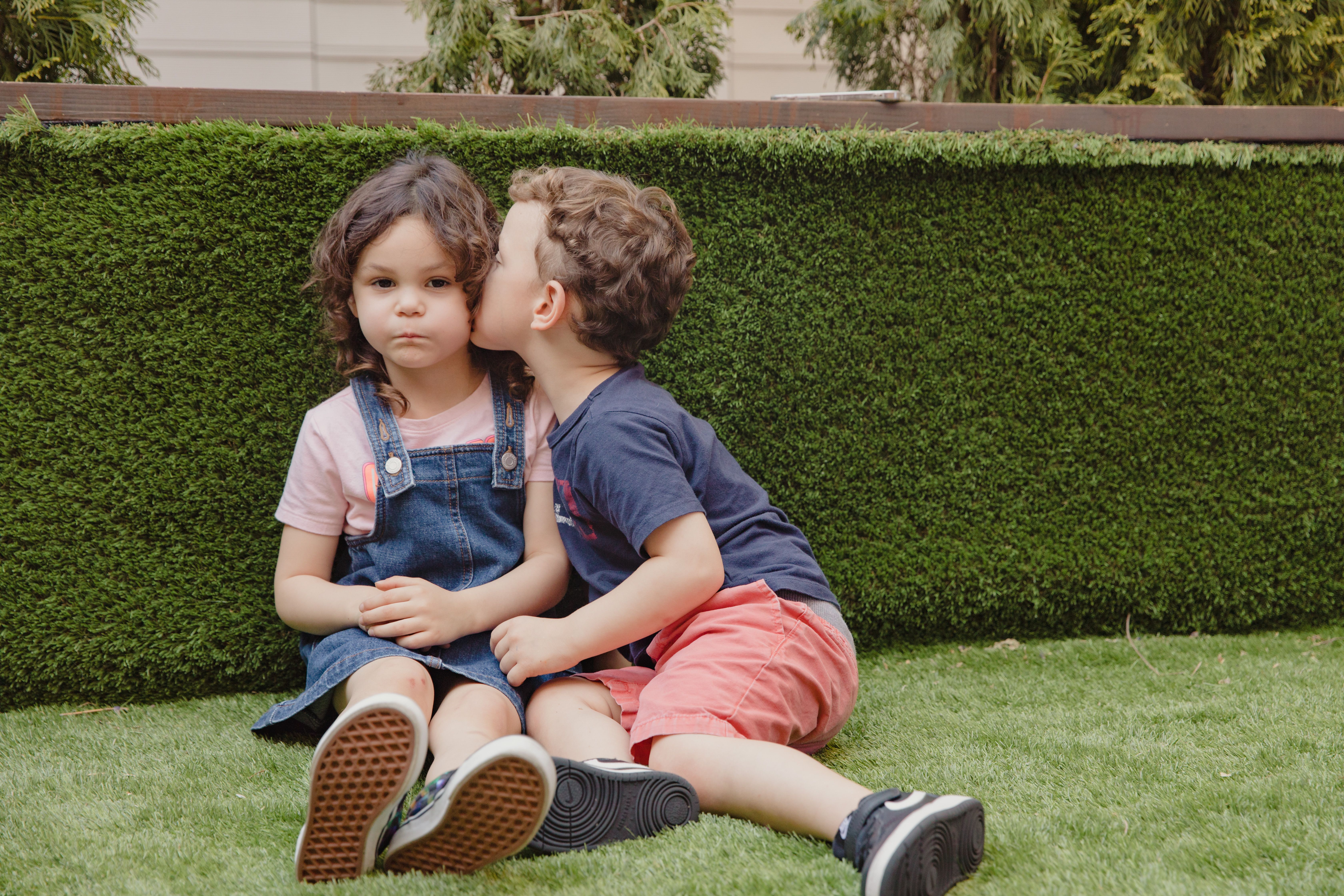 Boy kissing a girl while they sit in a garden (Representative Image Source: Pexels | photo by RDNE Stock Project)