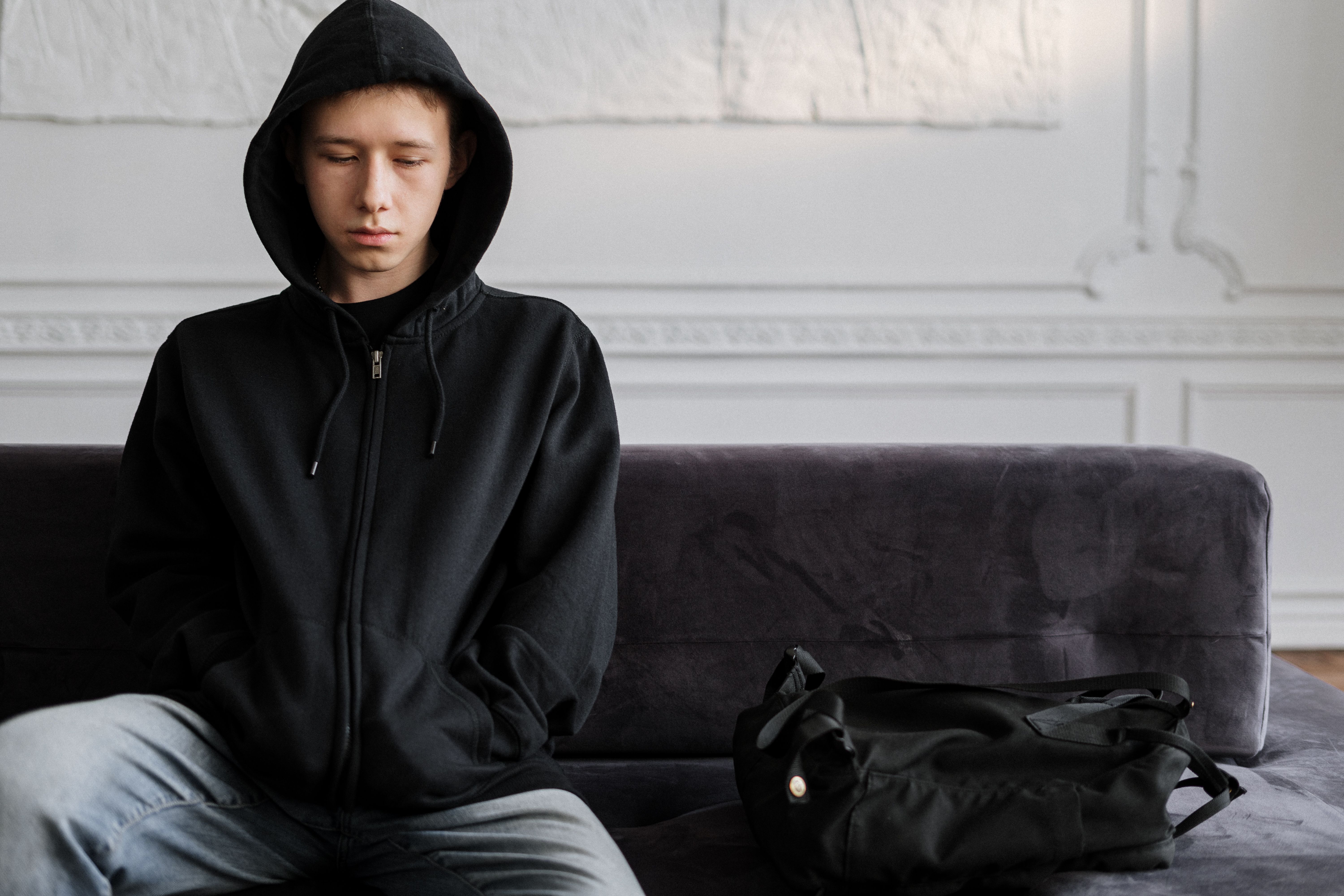 Teenager in hooded jacket sitting on a sofa (Representative Image Source: Pexels | Photo by Cottonbro Studio)