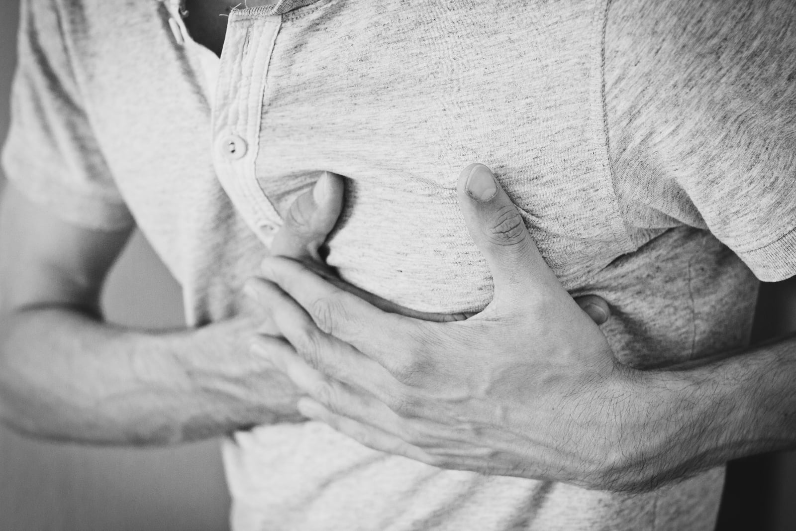 Black and white photo of a man clutching his chest, indicating discomfort or pain. (Representative Cover Image Source: Pexels | Photo by freestocks.org)