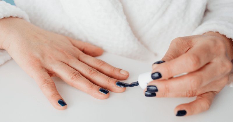 Close-up of a perspn applying dark nail polish (Representative Image Source: Pexels | Photo by https://kaboompics.com/