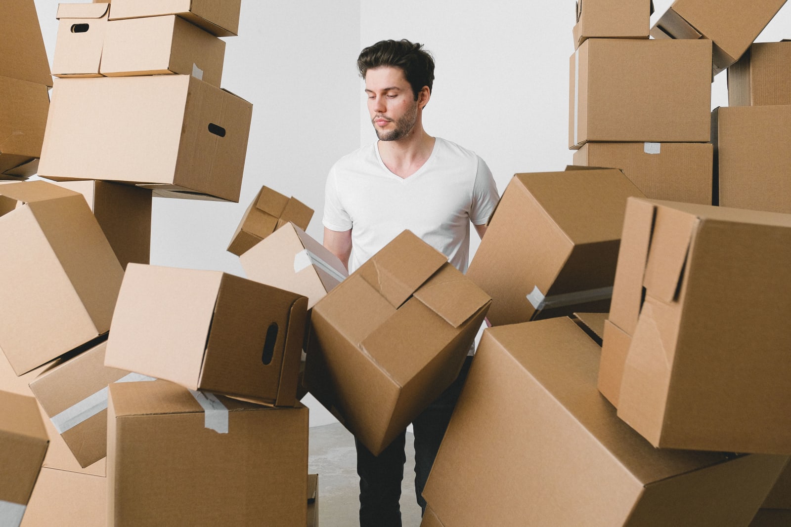 A young man surrounded by moving boxes indoors.