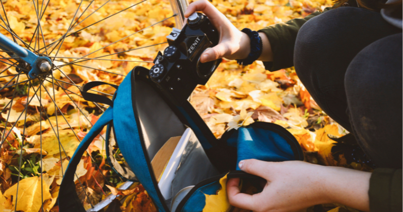 aWoman pitting a camera into a backpack (Representative Image Source: Pexels | Photo by Gergely Mesźarcsek)