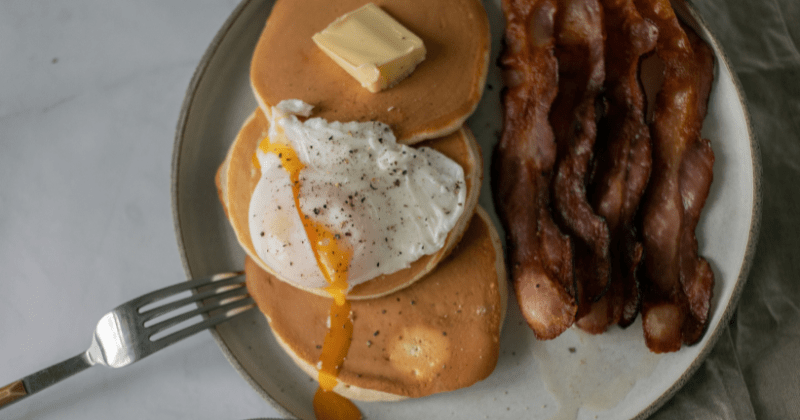Pancakes, poached egg, and crispy bacon on a plate (Representative Image Source: Pexels | Photo by Monstera Production)
