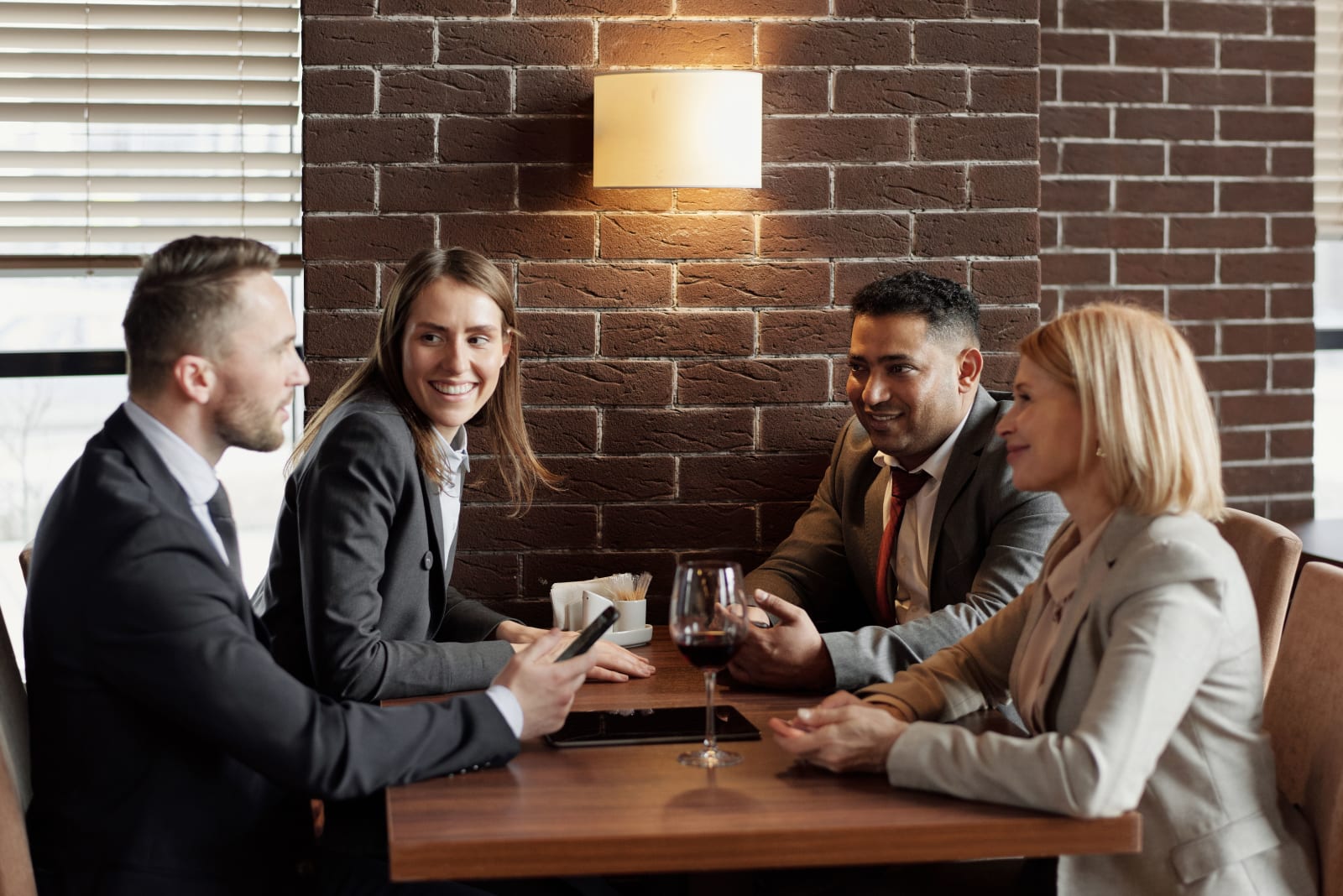 A group of business professionals having a lively discussion in a modern café. (Representative Cover Image Source: Pexels | Photo by August de Richelieu)