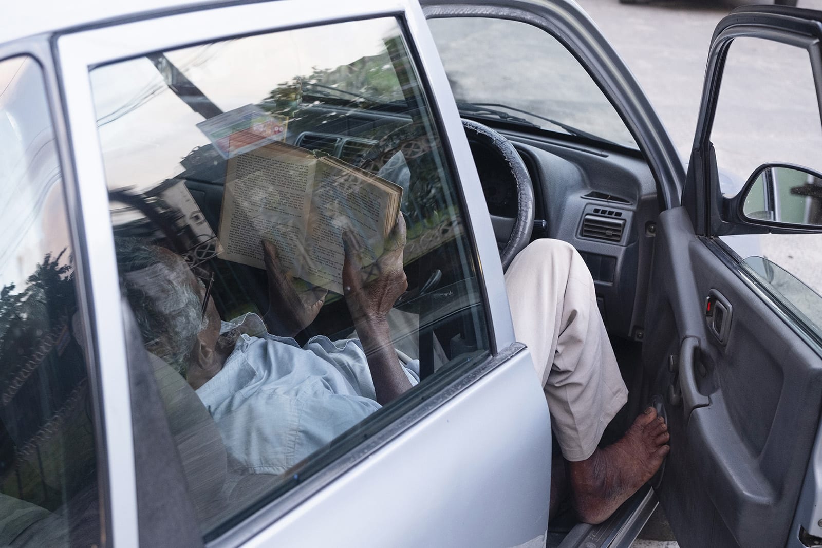 Taxi driver resting during the afternoon while poring over a book.