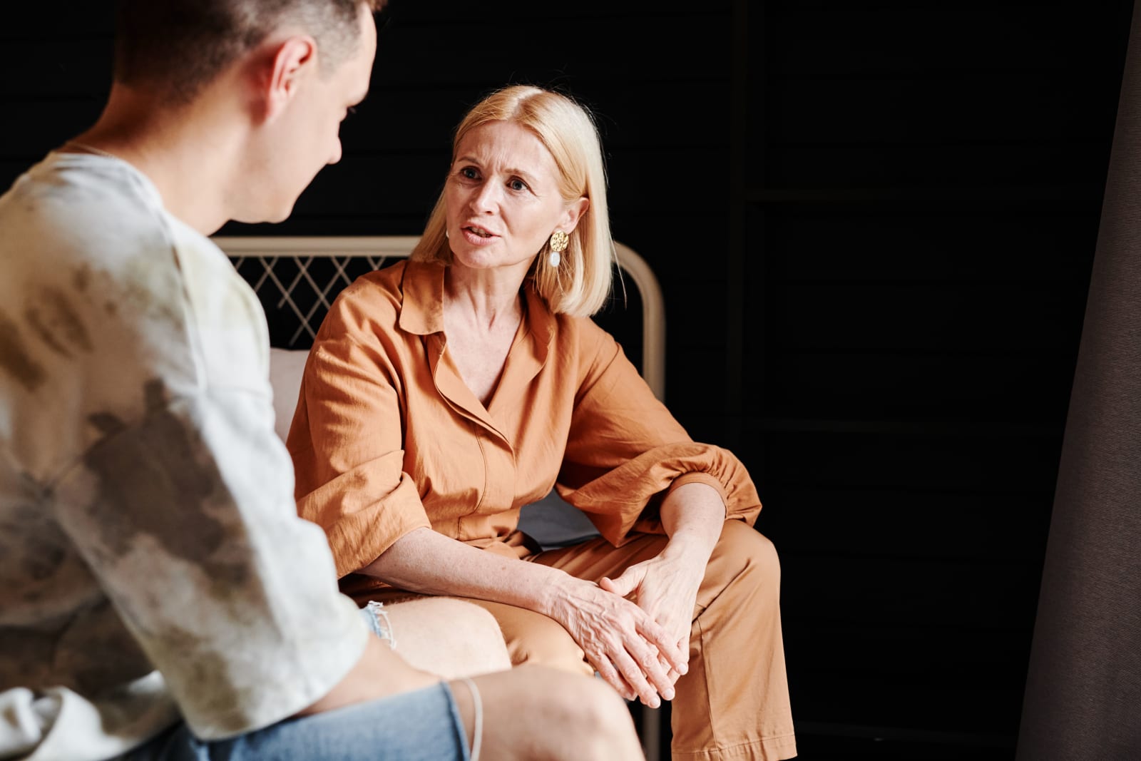 A candid moment of a mother and adult son having a heartfelt conversation indoors