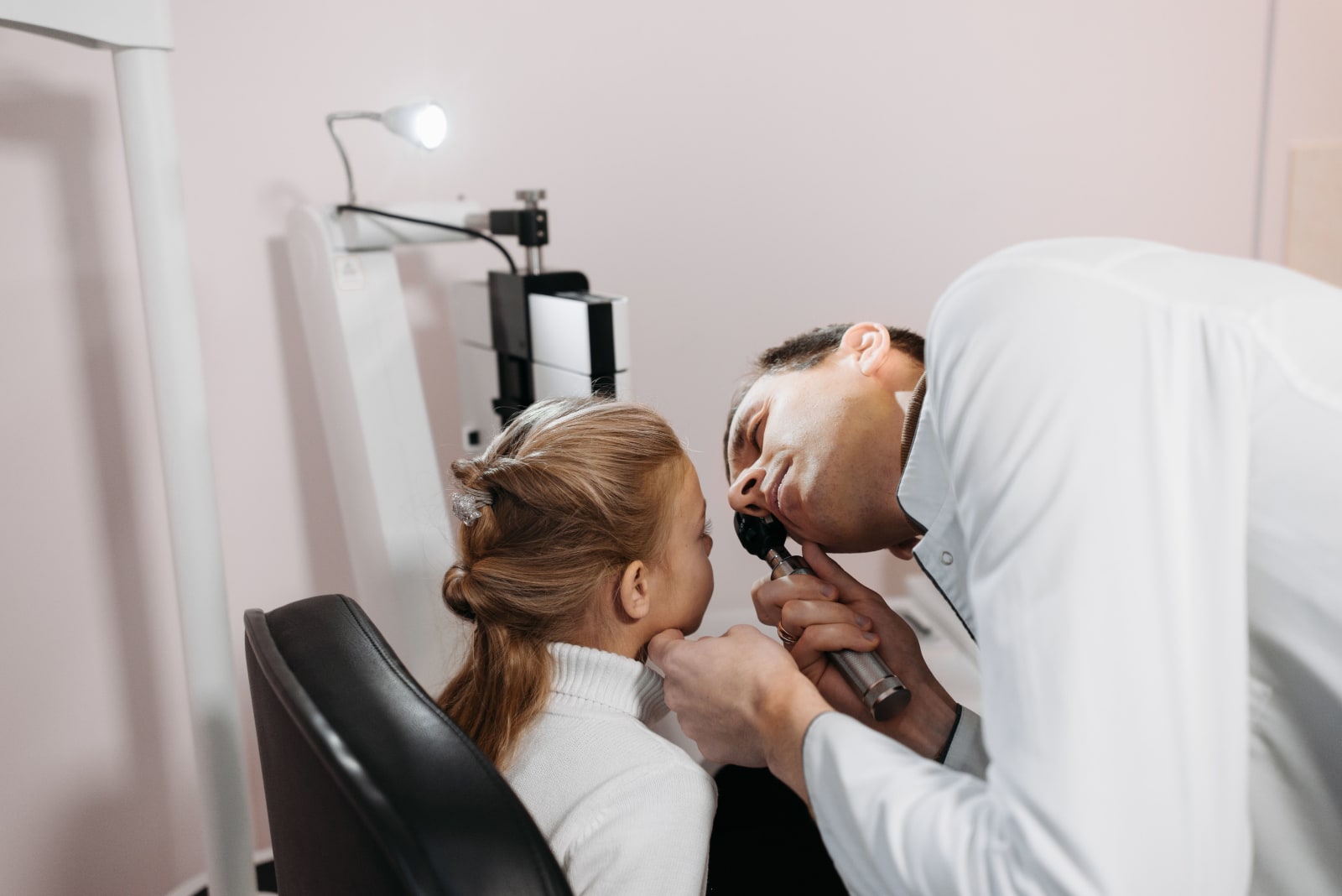 A doctor examines a young girl's ear during a medical appointment in a clinic