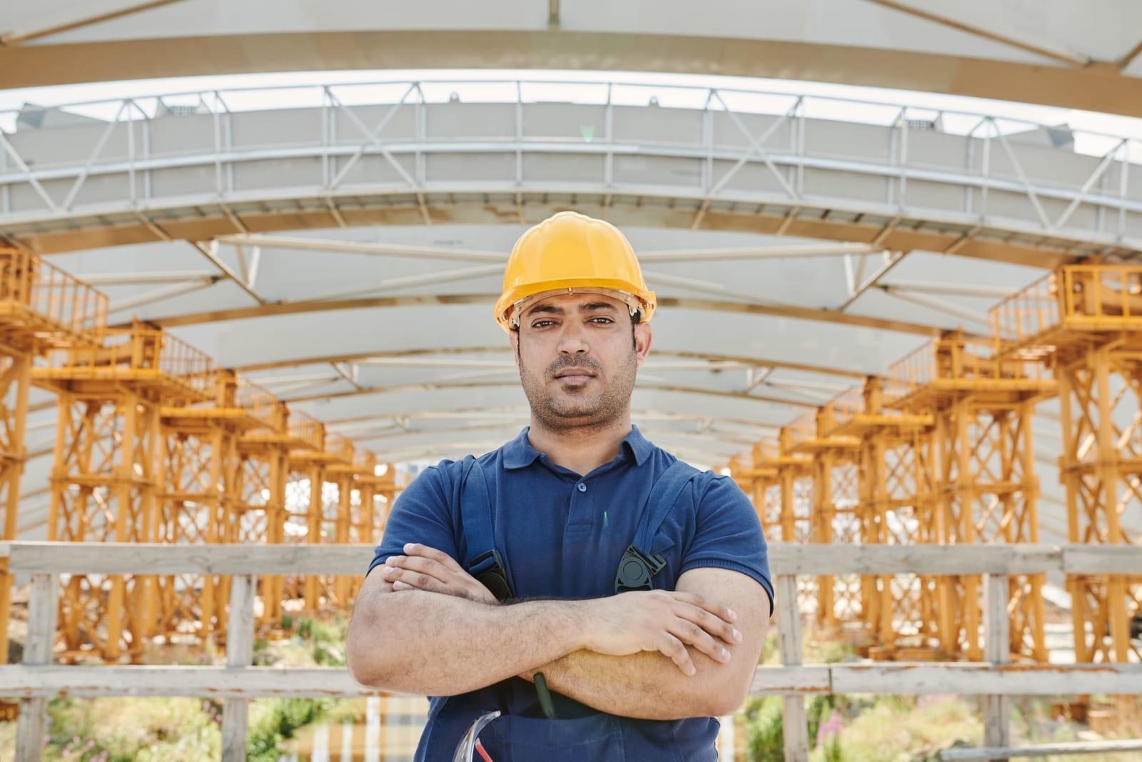 A male electrician standing against a construction plant (Representative Image Source: Pexels | Photo by Mikael Blomkvist)