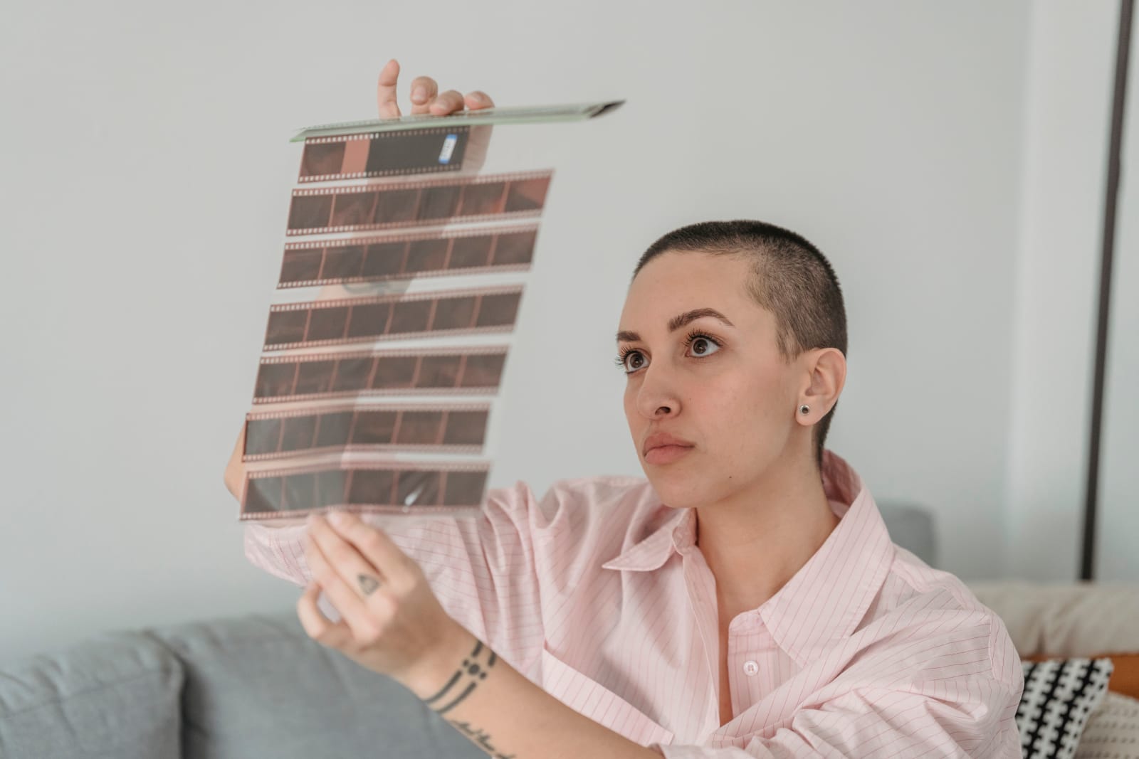 A thoughtful woman examines a film negative strip indoors. (Representative Cover Image Source: Pexels | Photo by George Milton)