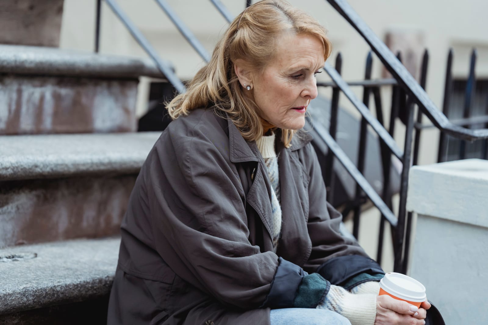 Old woman sitting on stairs with a cup of coffee (Representative Image Source: Pexels | Teona Swift)