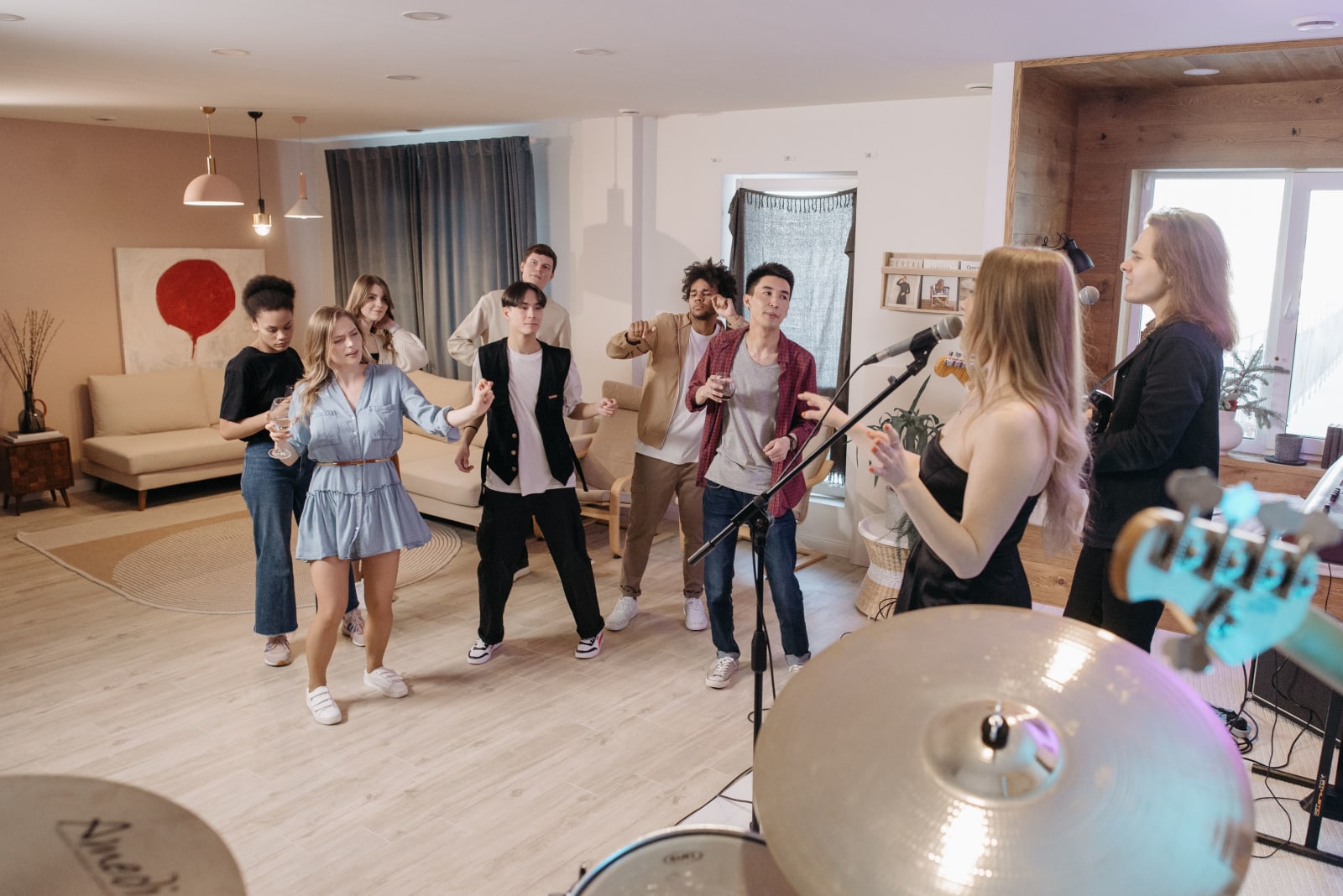 A lively indoor home party with a diverse group enjoying live music and dance.